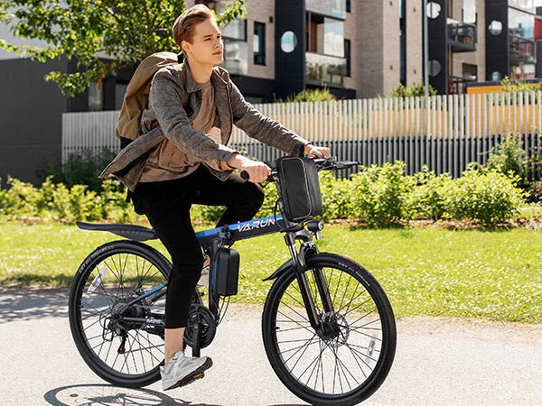 Young man riding blue Varun electric bike in urban park with backpack and casual clothes