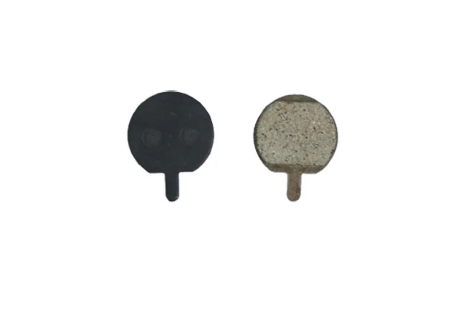 Close-up of two round bicycle brake pads, one black and one beige, isolated on white background
