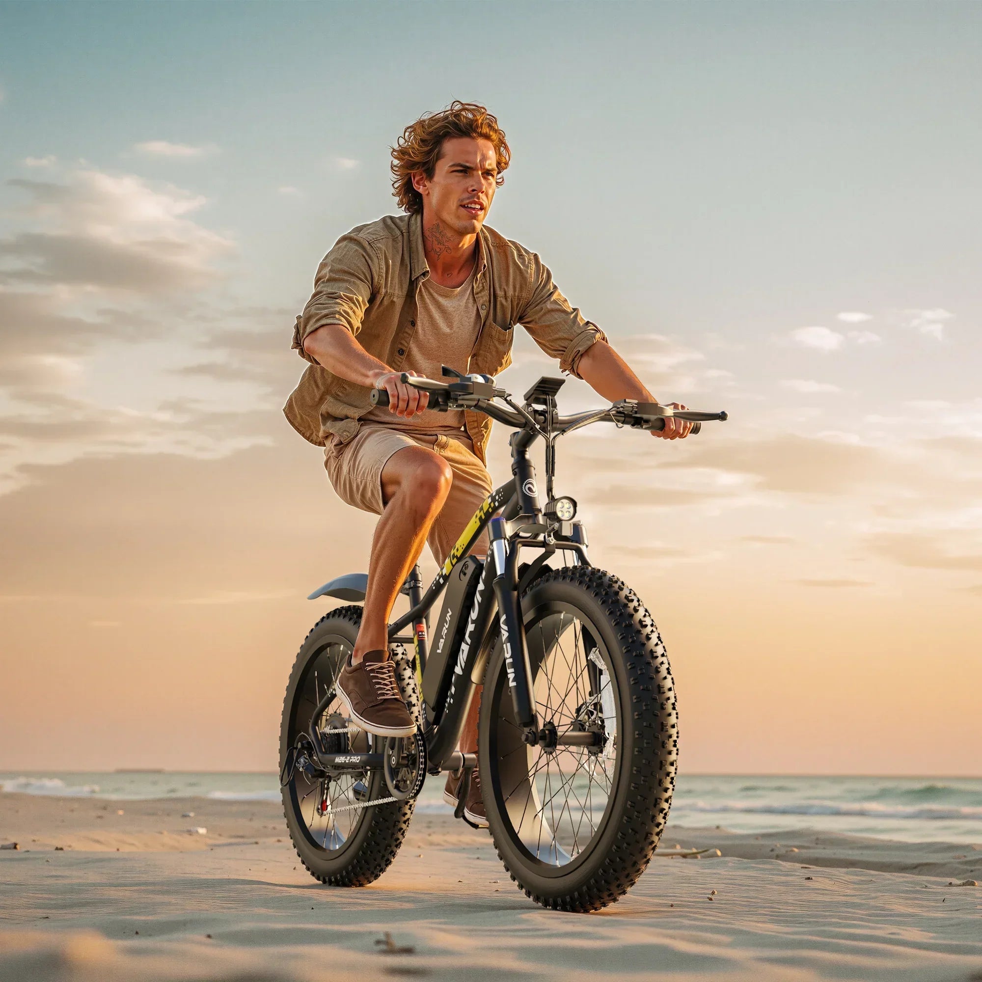 Man riding black fat-tire electric bike on sandy beach at sunset with casual outfit