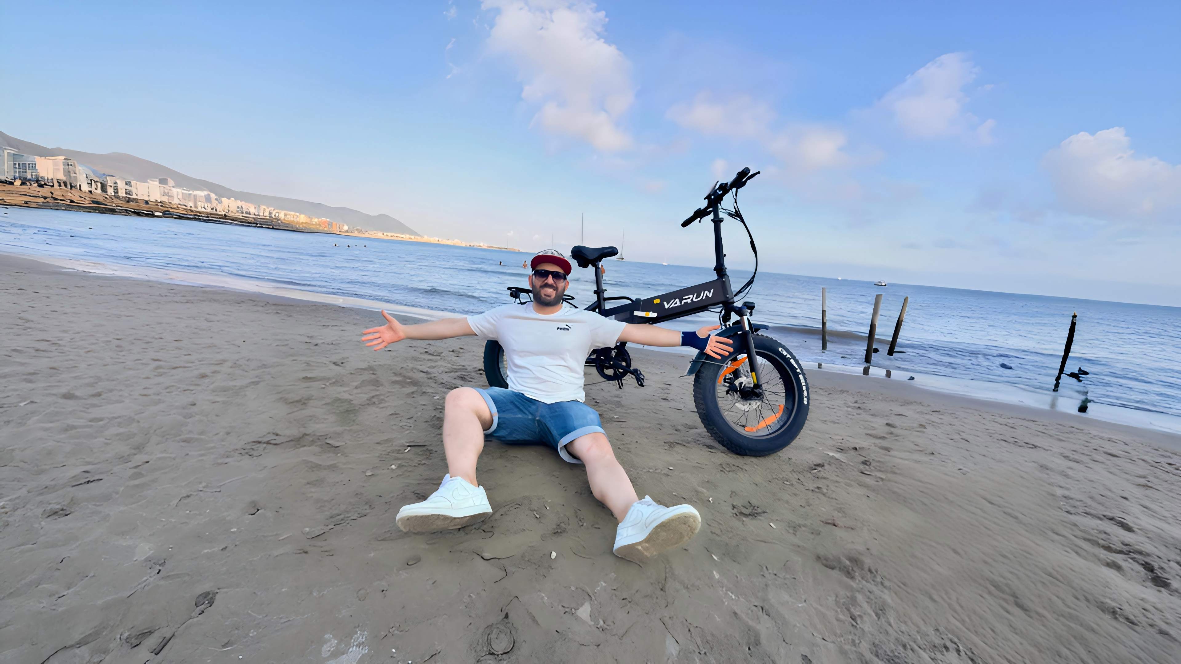 Smiling woman riding an orange electric fat tire bike on city street in casual summer outfit