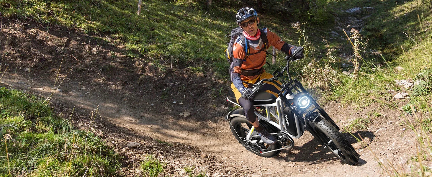 Man wearing helmet and gear riding a black and white electric mountain bike on rugged trail