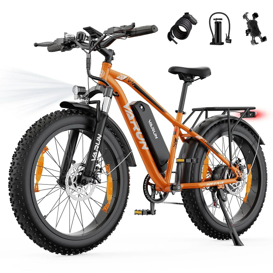 Orange Varun electric mountain bike with fat tires, front headlight, rear rack, and bike accessories