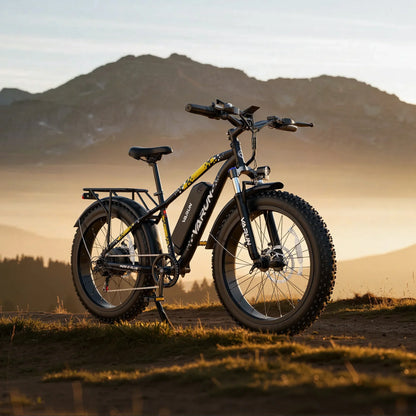 Black VARUN fat tire electric bike on grassy hill with mountain background at sunset